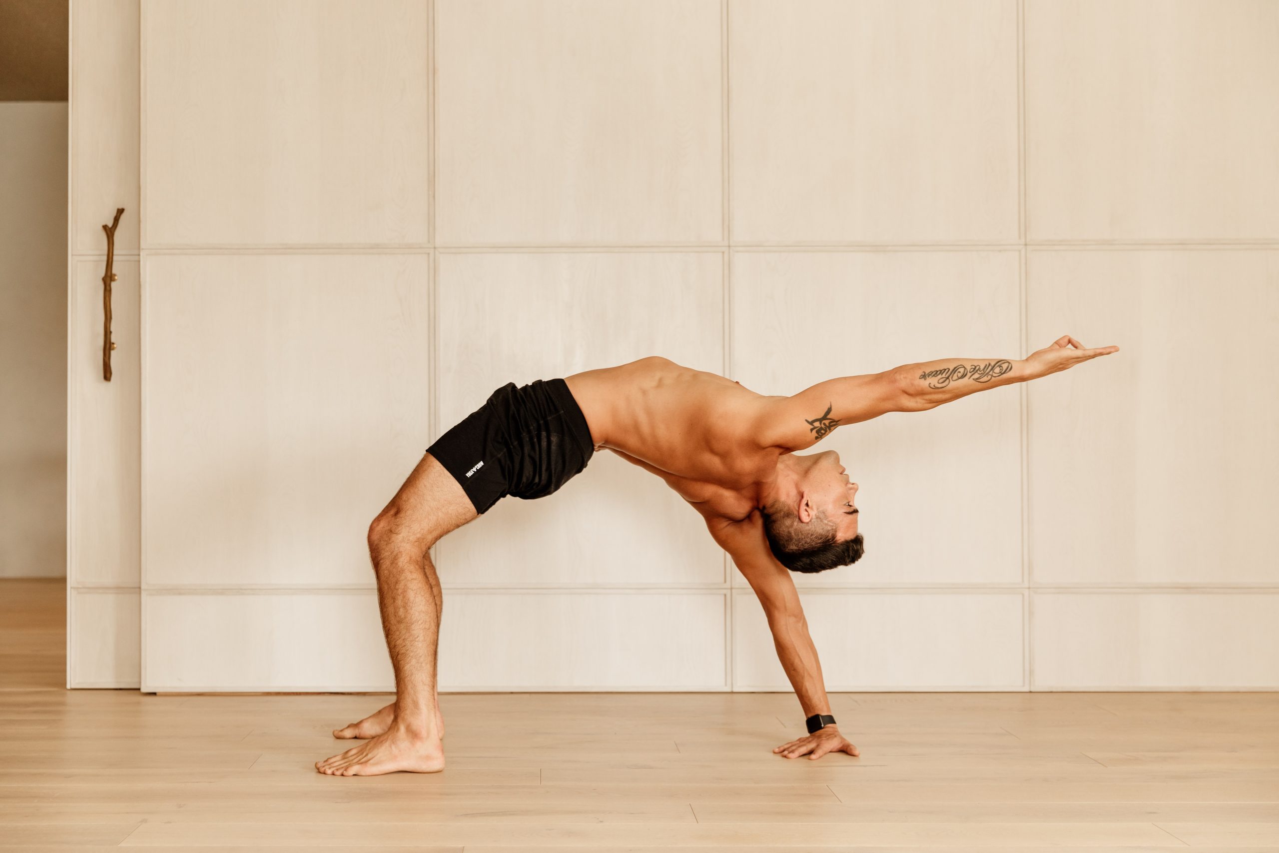 Yoga teacher Dustin Brown practicing a back bending yoga pose at warrior one yoga studio in Brighton