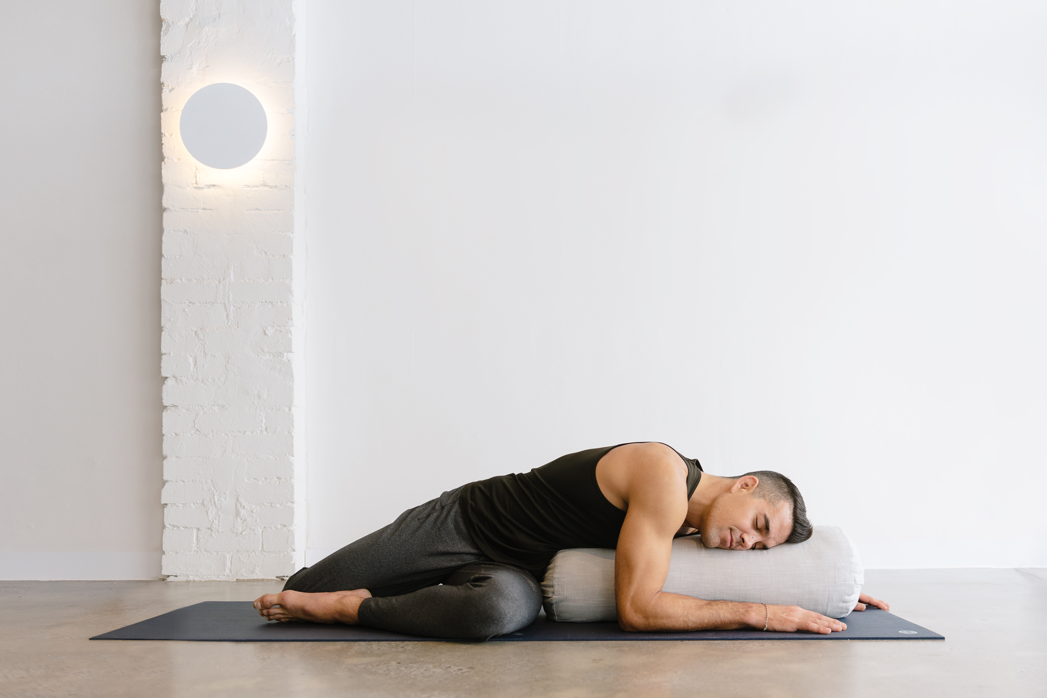 Yoga teacher Dustin Brown in a yin posture on a bolster at warrior one yoga studio in Mordialloc