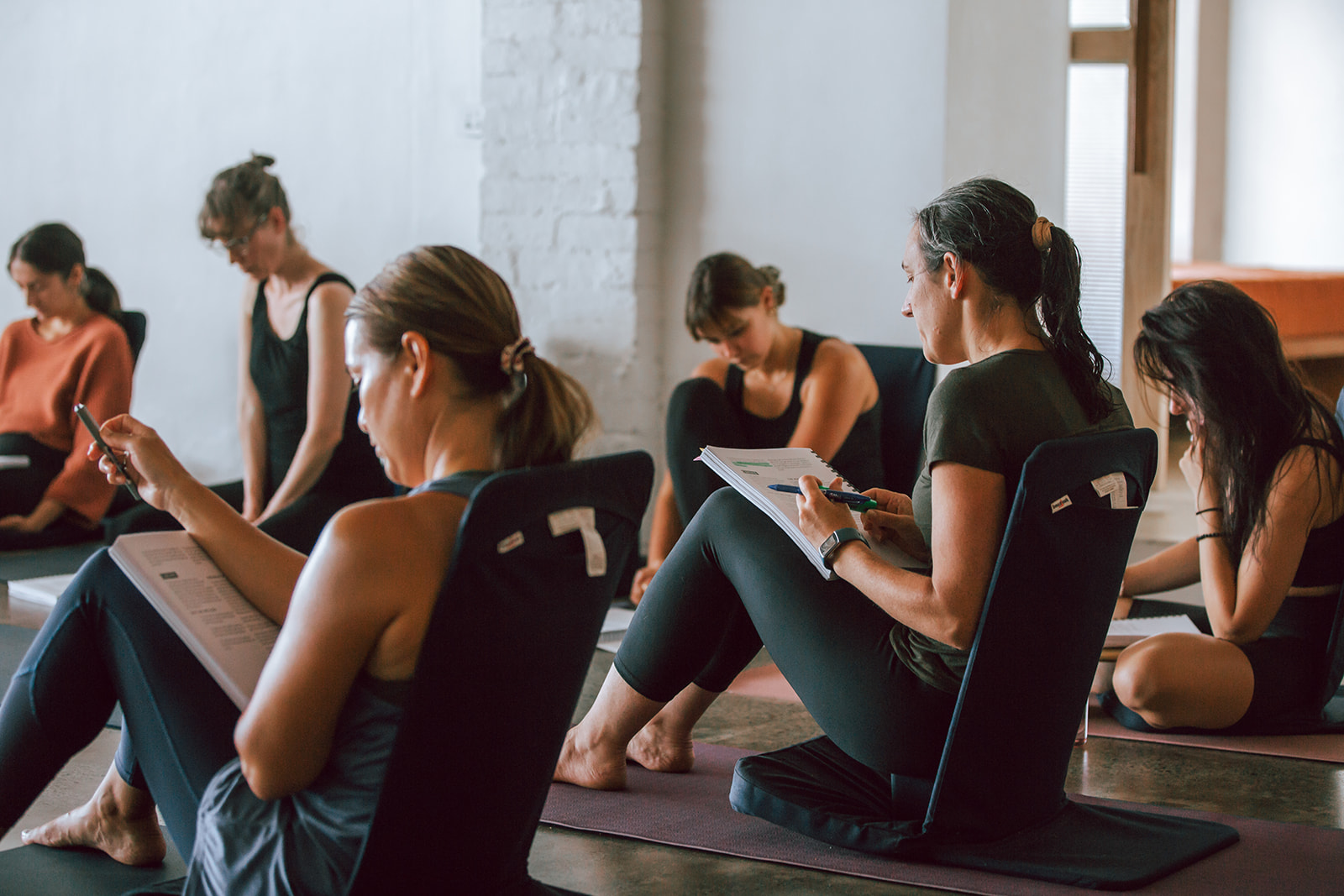 a group of teacher trainees studying their manuals at warrior one yoga in mordialloc participating in a 200 hour vinyasa yoga teacher training