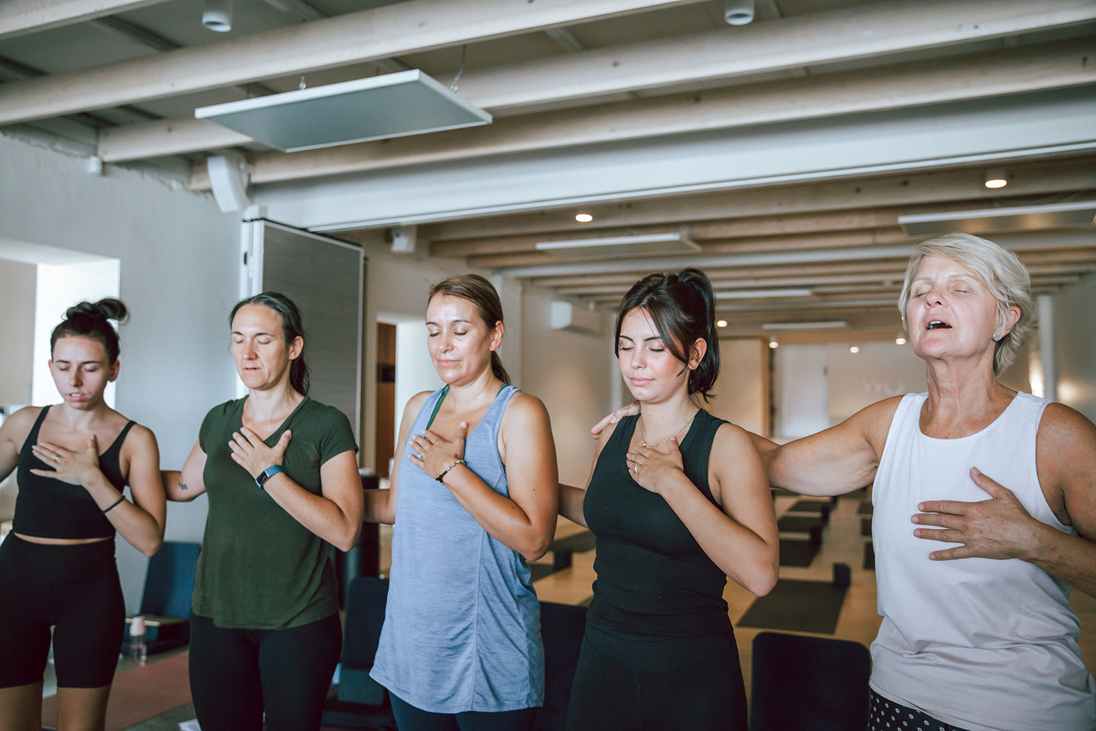 a group of students at warrior one yoga with their hands over their hearts and eyes closed as part of the 200 hour vinyasa teacher training in mordialloc