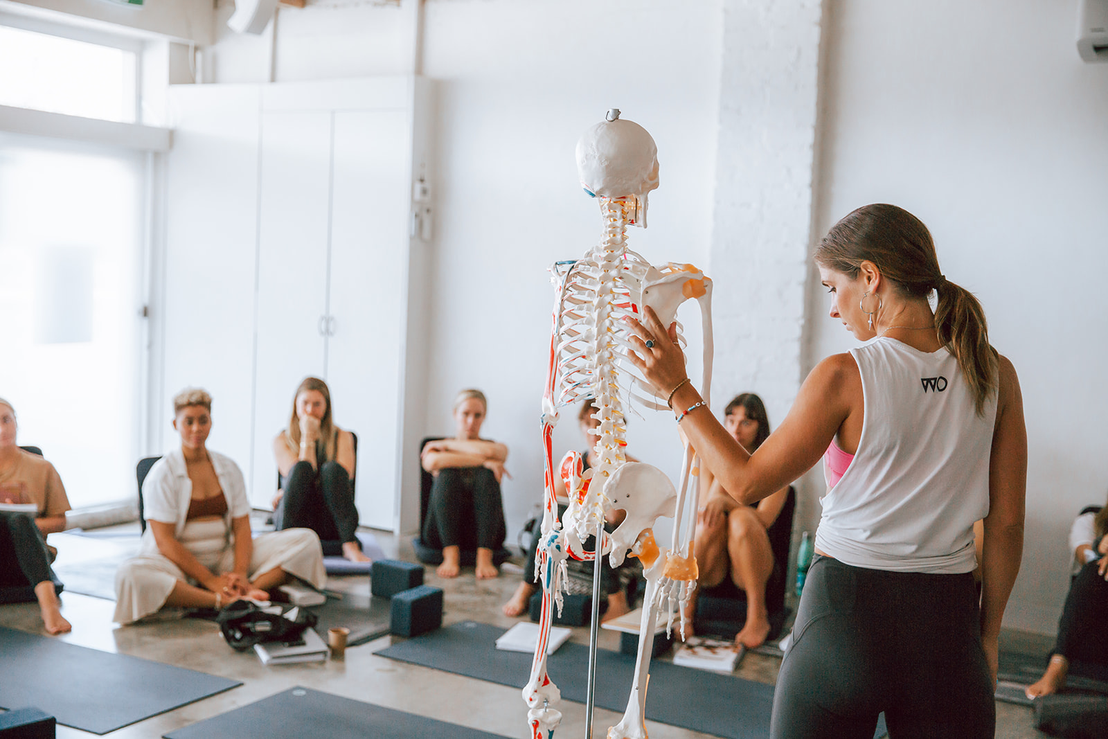 Yoga teacher Nat with an anatomy skeleton leading the 200 hour vinyasa yoga teacher training at Warrior One Yoga studio in Mordialloc